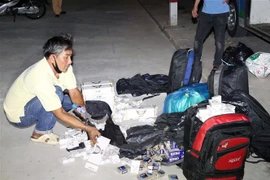Lái xe Văn Trí Dũng và số thuốc là nhập lậu bị thu giữ. (Ảnh: TTXVN phát)