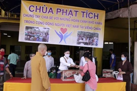 Để phòng chống dịch COVID-19, việc trao quà được tiến hành cho từng người một, đúng theo yêu cầu giãn cách của Bộ Y tế Lào. (Ảnh: Phạm Kiên/Vietnam+)