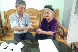 Cụ Mơ trao số tiền 2 triệu đồng cho lãnh đạo Mặt trận Tổ quốc xã Lương Sơn. (Ảnh: TTXVN phát)