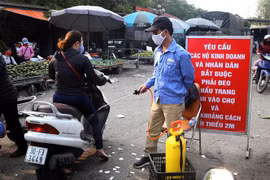 Các phương tiên được phun khử khuẩn tại các cửa ra vào chợ. (Ảnh: Danh Lam/TTXVN)
