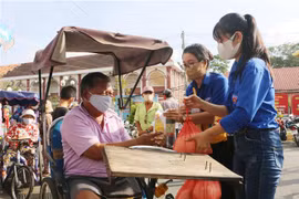 Lực lượng đoàn viên thanh niên hỗ trợ người dân nhận gạo miễn phí từ cây ATM gạo. (Ảnh: Chanh Đa/TTXVN)