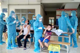 Các y, bác sỹ thăm khám, lấy mẫu xét nghiệm từng người trong khu cách ly. (Ảnh: Thanh Vũ-Tuấn Quang/TTXVN)