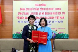 Chủ tịch Liên đoàn Lao động tỉnh Bắc Ninh Nguyễn Thị Vân Hà (trái) và Phó Chủ tịch Tổng Công hội tỉnh Chiết Giang Trương Vệ Hoa tại buổi ký kết bản ghi nhớ hợp tác. (Ảnh: Đinh Văn Nhiều/TTXVN)