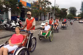 Khách du lịch nước ngoài thích thú khi chọn xíchlô làm phương tiện đi tham quan Đại Nội Huế. (Ảnh: Quốc Việt/TTXVN)