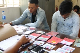 Các đối tượng cho vay nặng lãi cùng tang vật tại Công an phường 4, thành phố Tây Ninh. (Ảnh: Thanh Tân/TTXVN)