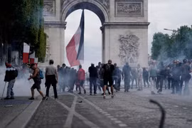 Cảnh sát phun hơi cay để giải tán đám đông người biểu tình quá khích tại đại lộ Champs Elysees ở thủ đô Paris, Pháp, ngày 14/7. (Ảnh: AFP/TTXVN)