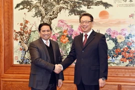 Ủy viên Bộ Chính trị, Bí thư Trung ương Đảng, Trưởng ban Tổ chức Trung ương Phạm Minh Chính và Ủy viên Bộ Chính trị, Bí thư Ban Bí thư, Trưởng Ban Tổ chức Trung ương Đảng Cộng sản Trung Quốc Trần Hy bắt tay thân mật. (Ảnh: Vĩnh Hà​/TTXVN)