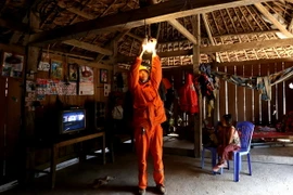 Công nhân Công ty Điện lực Thái Nguyên lắp đèn tiết kiệm điện và hướng dẫn người dân sử dụng điện an toàn. (Ảnh: Ngọc Hà/TTXVN)