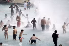 Người dân tránh nắng nóng bên vòi phun nước ở Paris, Pháp, ngày 26/6/2019. (Nguồn: THX/TTXVN) 
