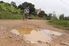 Mặt đường dở dang của dự án có các ổ voi, ổ gà tạo thành hố sâu rất dễ gây tai nạn. (Ảnh: Nguyên Lý/TTXVN) 
