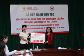 Bà Doãn Hải Hồng, Đại biện lâm thời Đại sứ quán nước Cộng hòa nhân dân Trung Hoa tại Việt Nam thay mặt Hội Chữ thập Đỏ Trung Quốc trao tặng số tiền 50.000 USD cho Chủ tịch Trung ương Hội Chữ thập đỏ Việt Nam Nguyễn Thị Xuân Thu. (Ảnh: Quý Trung/TTXVN)