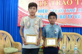 Hai em Bo Tý (trái) và Cao Lâm nhận Huy hiệu “Tuổi trẻ dũng cảm.” (Ảnh: Nguyên Lý/TTXVN)