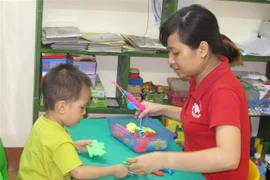 Giáo viên can thiệp, trị liệu và hỗ trợ hòa nhập cho trẻ tự kỷ ở Ninh Bình. (Ảnh: Thùy Dung/TTXVN) 