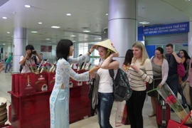 Các du khách Nga nhận món quà chiếc nón lá Việt Nam. (Ảnh: Tiên Minh/TTXVN)