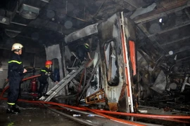 Các chiến sỹ phòng cháy chữa cháy dập lửa tại showroom. (Ảnh: An Hiếu/Vietnam+)