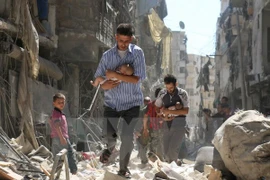 Chuyển các em nhỏ Syria ra khỏi một tòa nhà bị sập sau vụ không kích nhằm vào khu vực Salihin ở thành phố Aleppo, miền Bắc Syria ngày 11/9. (Nguồn: AFP/TTXVN)
