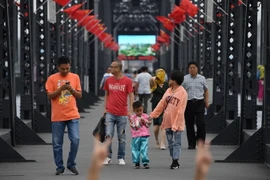 Du khách tham quan cây cầu Hữu Nghị nối giữa thành phố Dandong và thị trấn Sinuiju của Triều Tiên. (Nguồn: AFP/TTXVN)