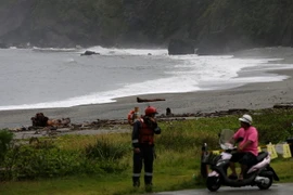 Lực lượng bảo vệ bờ biển (trái) khuyến cáo người dân không đến gần khu vực bờ biển trong bão Malakas tại Nghi Lan, Đài Loan ngày 17/9. (Nguồn: EPA/TTXVN)