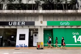 Văn phòng Grab (phải) và Uber (trái) tại Singapore ngày 26/3. (Nguồn: AFP/TTXVN)