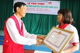 Chủ tịch Hội Chữ thập đỏ tỉnh An Giang Ngô Văn Sở (bìa trái) trao Bằng khen cho chị Phan Thị Mỹ Vân. (Ảnh: Vương Thoại Trung/TTXVN)