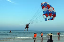 Khách du lịch tham gia trò chơi canô kéo dù tại biển Phạm Văn Đồng (Đà Nẵng). (Ảnh: Trần Lê Lâm/TTXVN) 
