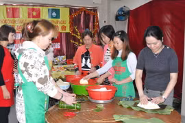 Phó Tổng Lãnh sự Vũ Chi Mai (ngoài cùng bên phải) gói bánh chưng cùng bà con lao động tại Macau. (Ảnh: Vietnam+)