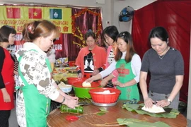 Phó Tổng Lãnh sự Vũ Chi Mai (ngoài cùng bên phải) gói bánh chưng cùng bà con lao động tại Macau. (Ảnh: Vietnam+)