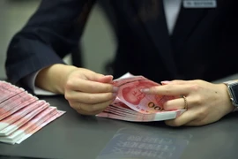 Nhân viên ngân hàng kiểm tiền 100 nhân dân tệ mới tại một ngân hàng ở thủ đô Bắc Kinh ngày 12/11. (Nguồn: THX/TTXVN)