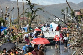 Người dân Philippines bên đống đổ nát, ngày 10/11. (Ảnh: AFP/TTXVN)