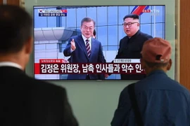 Người dân Hàn Quốc tại thủ đô Seoul theo dõi hình ảnh truyền hình trực tiếp Nhà lãnh đạo Triều Tiên Kim Jong-un (phải, phía xa) đón Tổng thống Hàn Quốc Moon Jae-in (trái, phía xa) tại sân bay quốc tế Bình Nhưỡng ngày 18/9/2018. (Nguồn: AFP/TTXVN)