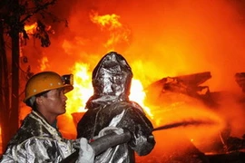 Lực lượng phòng cháy chữa cháy nỗ lực dập lửa. (Ảnh: Văn Đức/Vietnam+)
