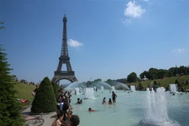 Người dân tránh nắng nóng bên vòi phun nước ở Paris, Pháp, ngày 26/6/2019. (Nguồn: THX/TTXVN) 