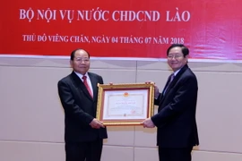 Bộ trưởng Bộ Nội vụ Việt Nam Lê Vĩnh Tân trao Quyết định tặng Huân chương Độc lập hạng Nhì của Nhà nước Việt Nam cho Bộ trưởng Nội vụ Lào Khamman Sonvileuth. (Ảnh: Phạm Kiên/TTXVN)