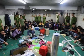 Các đối tượng liên quan cùng tang vật bị Công an bắt giữ tại sới bạc. (Nguồn: TTXVN) 