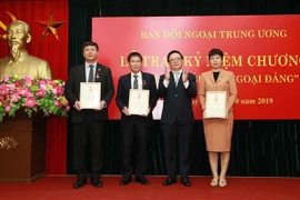Ông Hoàng Bình Quân, Ủy viên Trung ương Đảng, Trưởng Ban Đối ngoại Trung ương trao tặng Kỷ niệm chương 'Vì sự nghiệp Đối ngoại Đảng' cho Phó Tổng Giám Vũ Việt Trang và hai Trưởng ban Biên tập của TTXVN. (Ảnh: Doãn Tấn/ TTXVN) 