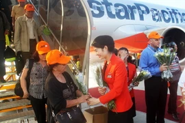 Nhân viên Jestar Pacific tặng hoa cho hành khách. (Ảnh :Thế Lập/TTXVN)