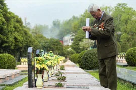 Một cựu chiến binh thắp hương cho đồng đội tại Nghĩa trang Liệt sỹ A1. (Ảnh: Xuân Tư/TTXVN) 