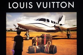 Một người đàn ông bên ápphích quảng cáo bên ngoài cửa hàng Louis Vuitton ở Trung Quốc. (Nguồn: THX/TTXVN)