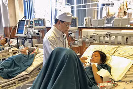 Bác sỹ chuyên khoa 2, Phạm Ngọc Kiếu, Trưởng khoa Hồi sức Tích cực, Bệnh viện Đa khoa Trung tâm An Giang thăm khám cho bệnh nhân Nguyễn Hồng Kim C. (Ảnh: Thanh Sang/ TTXVN) 