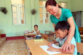 Cô giáo Vũ Thị Hà đang hướng dẫn học sinh lớp 2, Trường tiểu học Bạch Long Vỹ, học bài. (Ảnh: Minh Thu/TTXVN) 