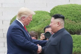 Tổng thống Mỹ Donald Trump (trái) bắt tay nhà lãnh đạo Triều Tiên Kim Jong-un (phải) trong cuộc gặp ở làng đình chiến Panmunjom tại Khu phi quân sự (DMZ) chiều 30/6/2019. (Nguồn: Yonhap/TTXVN) 