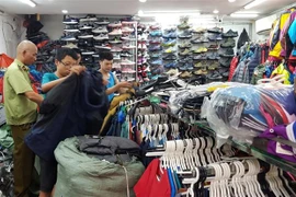 Lực lượng quản lý thị trường kiểm tra, phát hiện nhiều sản phẩm giả thương hiệu The North Face tại cửa hàng kinh doanh quần áo, giầy dép số 62 Lò Sũ, quận Hoàn Kiếm. (Ảnh: Trần Việt/TTXVN) 