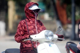 Người dân mặc kín mít để tránh nắng nóng khi ra đường. (Ảnh: Thế Duyệt/TTXVN)