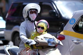 Nhiều người lớn và trẻ em đều được bịt kín toàn thân khi lưu thông trên đường phố Hà Nội. (Ảnh: Quý Trung/TTXVN)