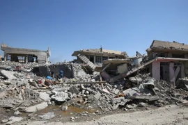 Người dân Iraq dọn dẹp những đống đổ nát sau các vụ không kích. (Nguồn: AFP/TTXVN)