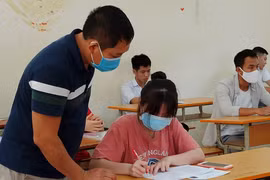 Thí sinh và giám thị cùng đeo khẩu trang vào phòng thi trong kỳ thi Tốt nghiêp Trung học phổ thông 2020. (Ảnh: Phạm Mai/Vietnam+)