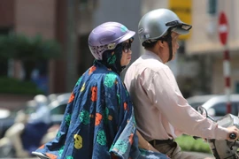 Người dân ra đường với trang phục kín mít để tránh cái nắng gay gắt. (Ảnh: Thành Đạt/TTXVN)