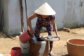 Do giếng đào của gia đình đã khô cạn, bà Dương Thị Hồng, 70 tuổi, thôn Suối Phèn, xã Sơn Long, huyện Sơn Hòa hàng ngày vẫn phải đi xin từng gàu nước sinh hoạt về dùng. (Ảnh: Phạm Cường/TTXVN)