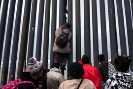 Người di cư Trung Mỹ trèo qua bức tường biên giới Mỹ-Mexico tại Playas de Tijuana, bang Baja California, Mexico, ngày 21/3/2019. (Nguồn: AFP/TTXVN)