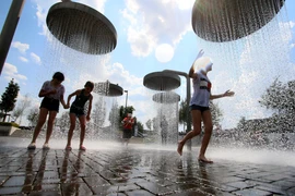 Trẻ em chơi đùa dưới vòi phun nước để tránh nắng nóng tại Vilnius, Lítva, ngày 13/6/2019. (Nguồn: AFP/TTXVN)